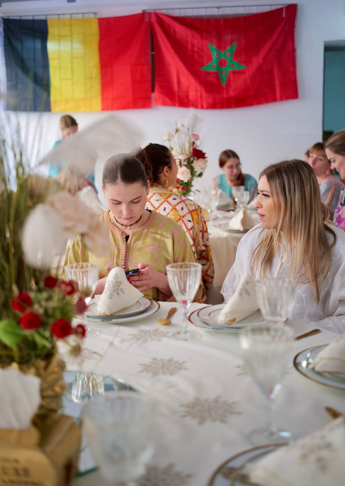 International exchange students wearing Moroccan caftans at a traditional meal, under the Belgian and Moroccan flags